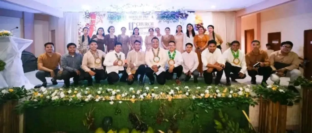The missionary pastors and their wives on stage under the church's 11th anniversary banner